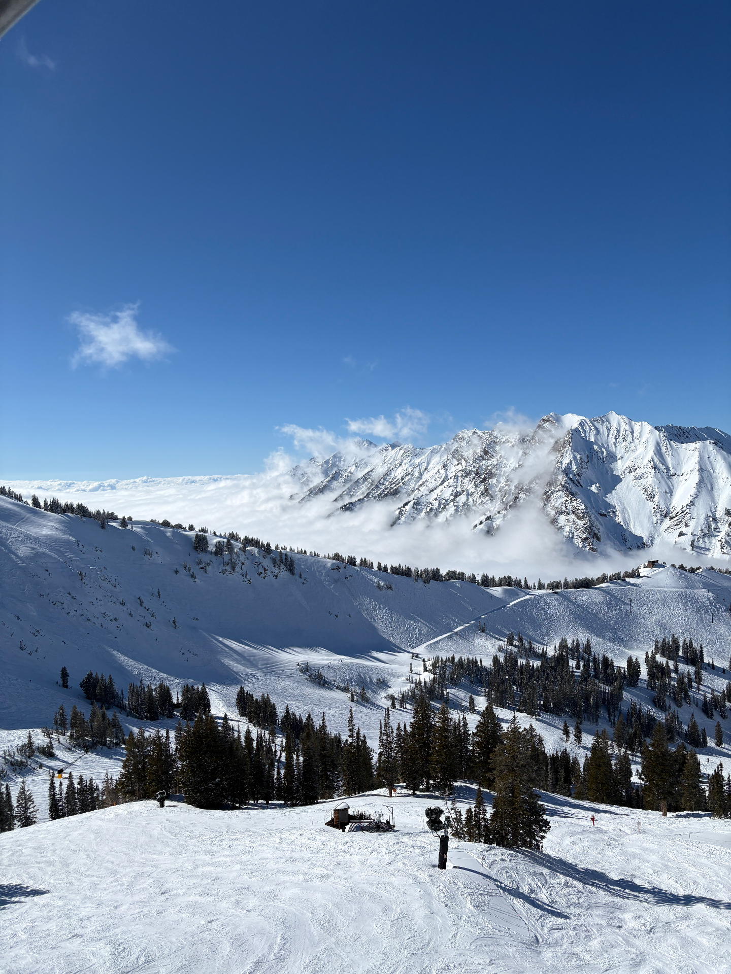 Snow-covered alpine ridgeline above an inversion cloud layer under a deep blue sky