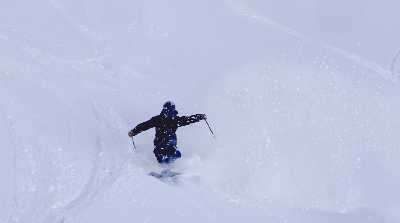 Oskar Lighthiser sinking into deep powder on a steep snowfield, snow exploding around him