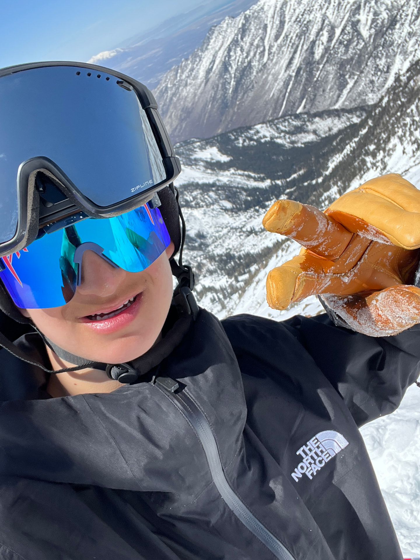 Oskar Lighthiser in goggles and sunglasses smiling on a ridge above the Pipeline couloir