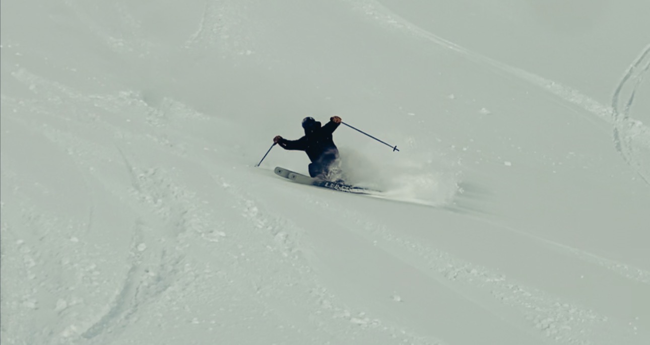 Oskar Lighthiser carving a powder turn on a steep snow slope