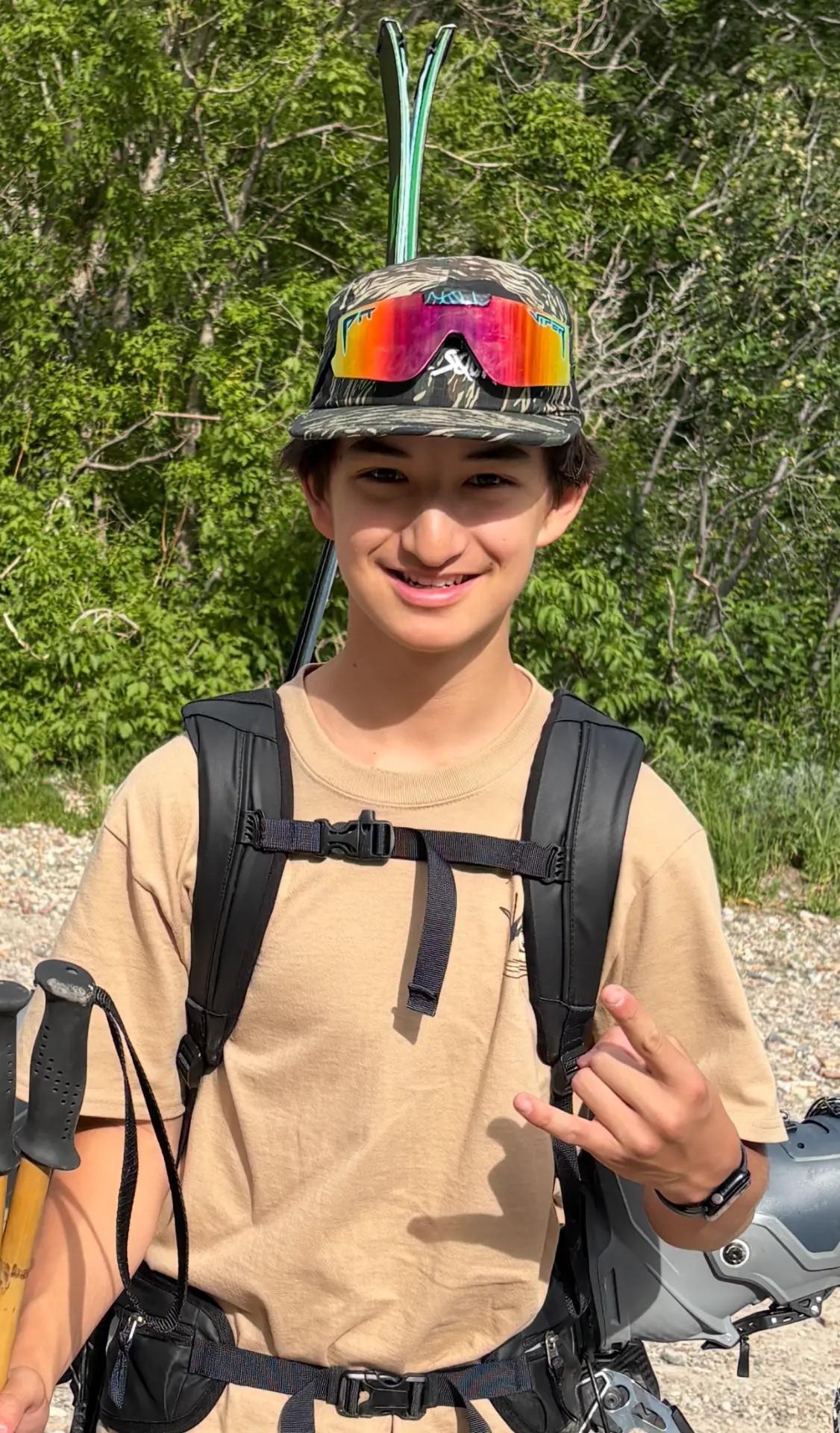 Oskar Lighthiser smiling on a backcountry ski tour approach, skis strapped to his pack and poles in hand