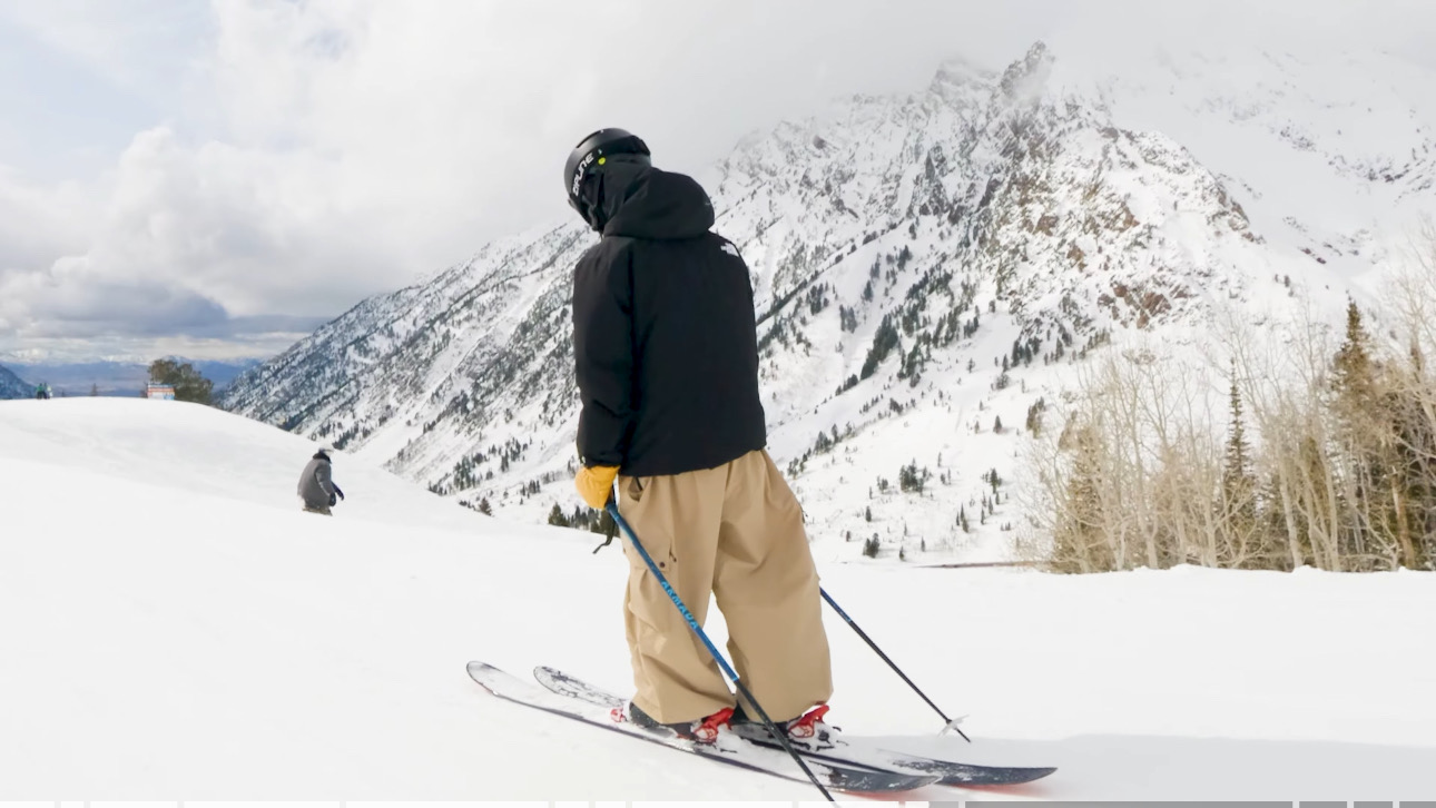 Oskar Lighthiser standing on skis at the top of a run, looking out at a snow-covered peak